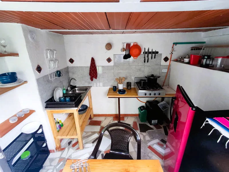 Cocina equipada con estufa, lavaplatos, nevera, utensilios y mesa de comedor