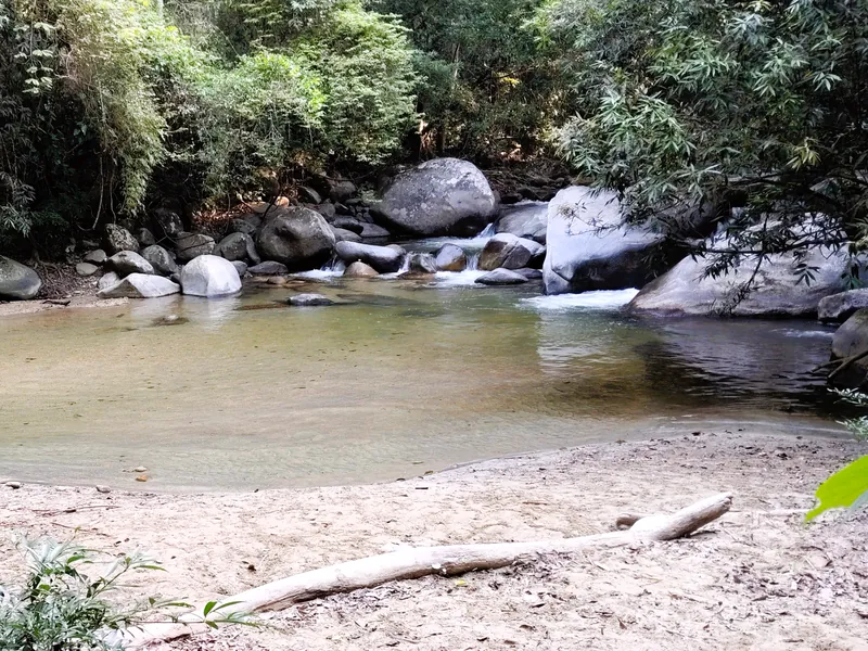 Río de aguas cristalinas entre rocas, con una pequeña playa de arena