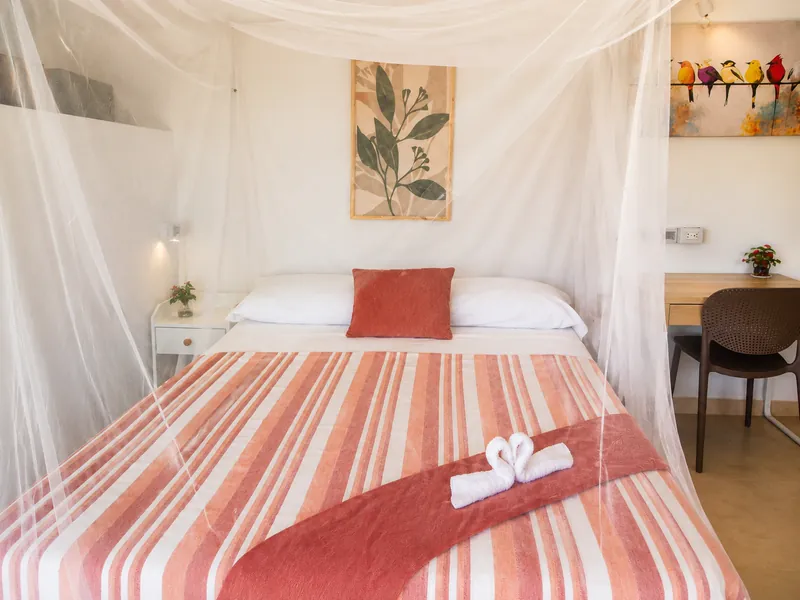 Detalle de la cama con colcha de rayas, cisnes de toalla y mosquitero