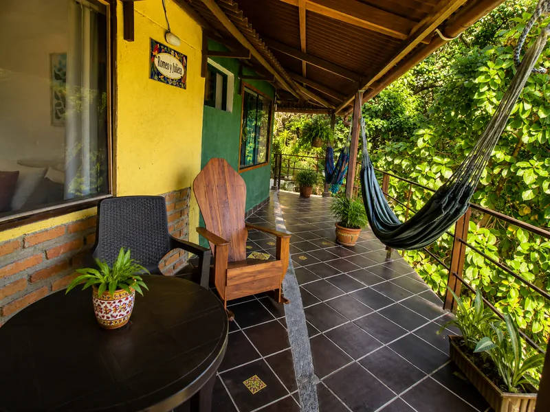 Terraza techada con mecedora de madera, mesa y hamacas junto a la placa de Romeo y Julieta